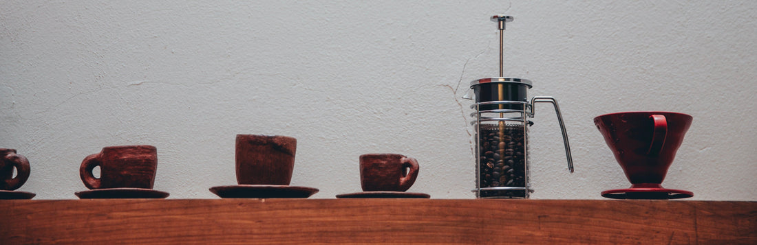 Coffee cups in different sizes and a french press, a pour-over coffee dripper