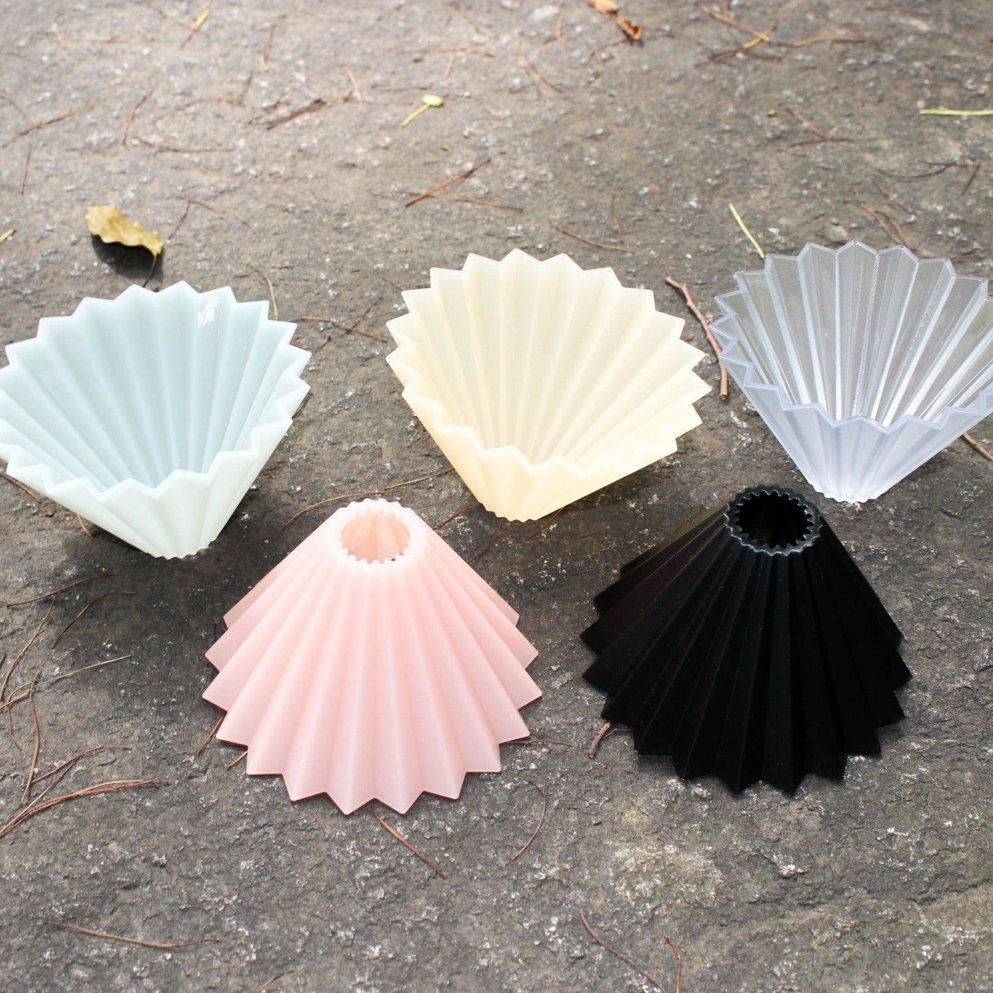 There are 5 ORIGAMI Dripper Air on ground, they are matte green, matte pink, matte beige, clear and black