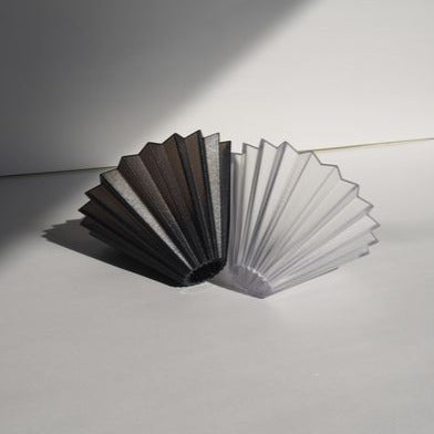 A blak and a clear ORIGAMI Dripper Air next to each other on ground, the light source is from right side