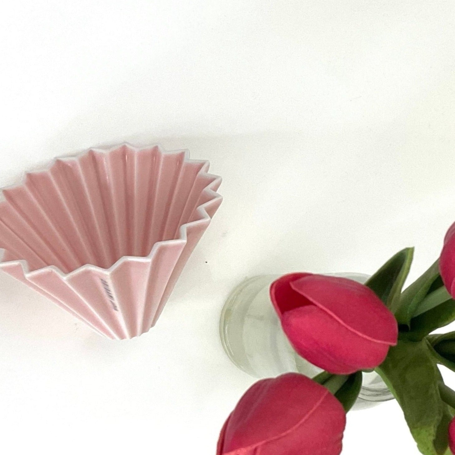 A Matte Pink Origami Coffee Dripper next to a Tulip Bouquet 