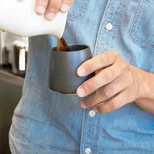 A man is pouring coffee into a matte black ORIGAMI Aroma Flavor Cup