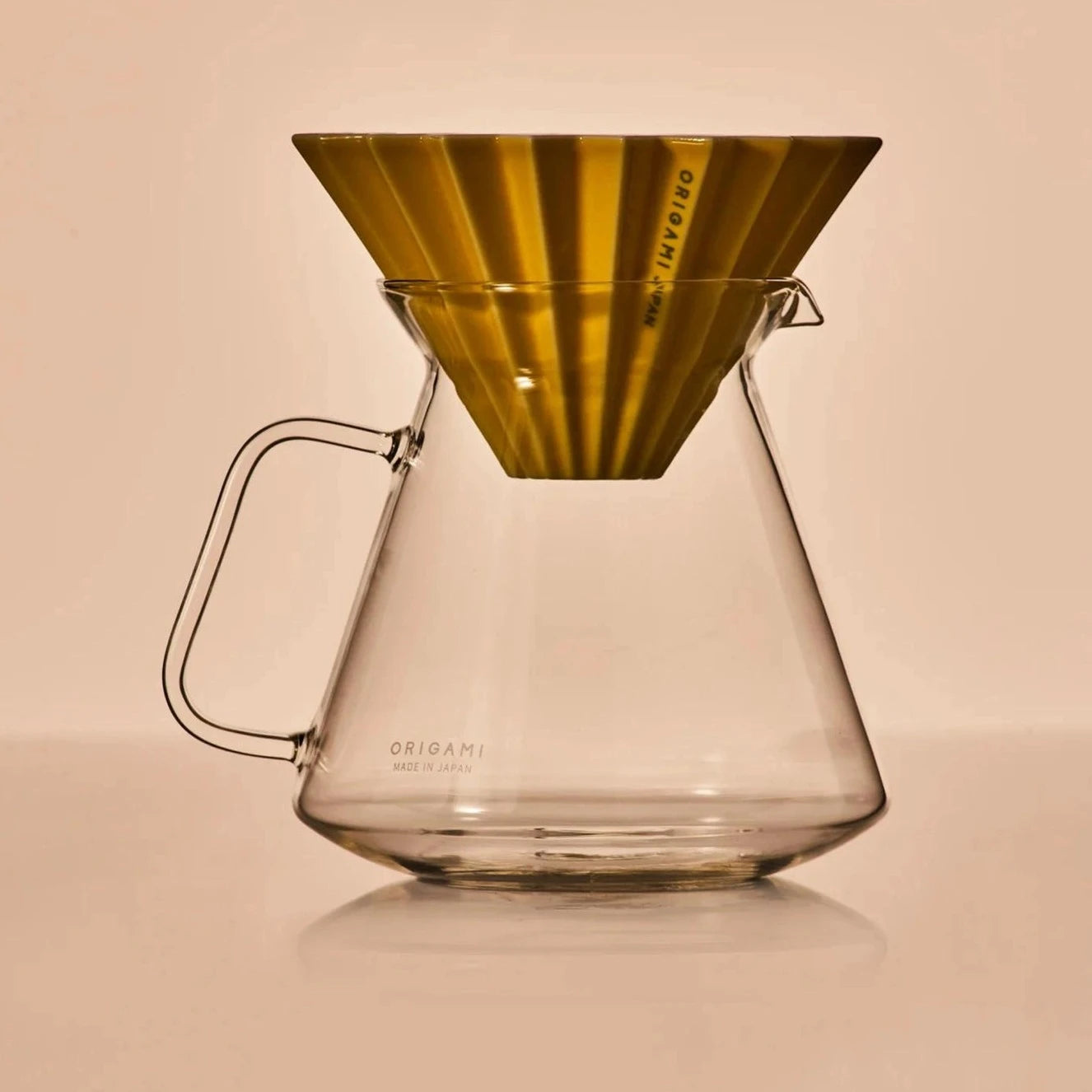 a gold color ORIGAMI porcelain dripper on ORIGAMI x HARIO glass coffer server