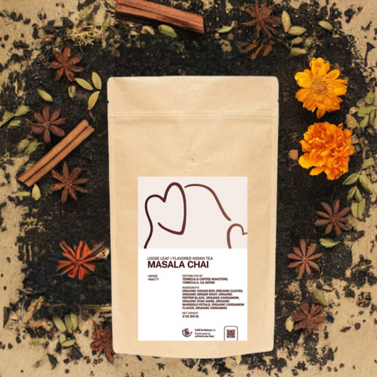 A bag of Flavored Indian Tea Masala Chai surrounded with loose leaf tea, star anise, and spices