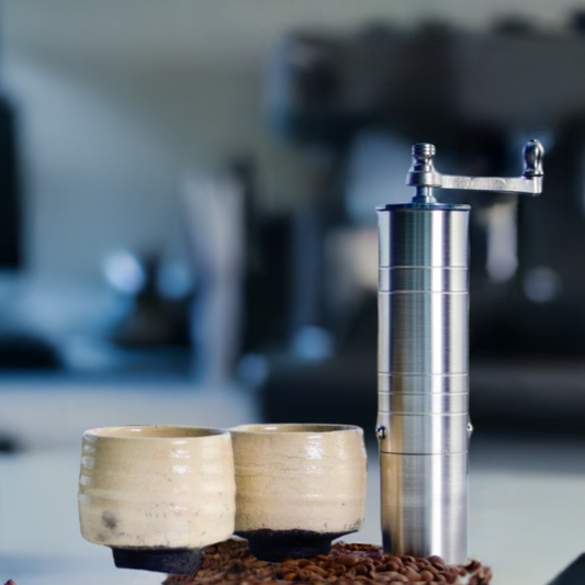 An Athena 7.7" Coffee Grinder on a kitchen countertop, two ceramic flavor cups are next to it. The backdrop is blur, and  blue color kitchen scene 