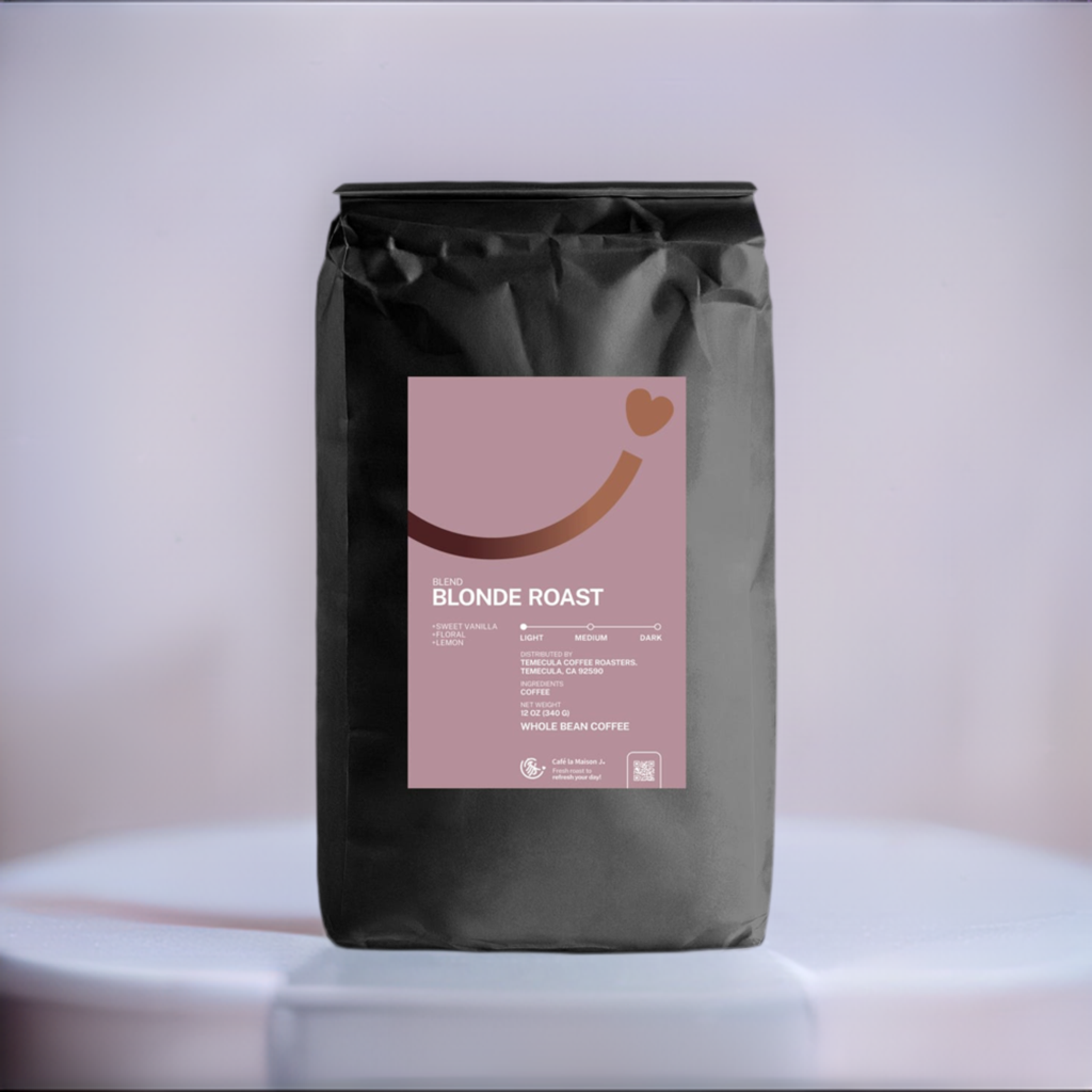 a bag of coffee bean, 12oz, light roasted BLONDE ROAST, the label is mauve color with a brown gradient smiley line and a heart at the end of the smiley line. The bag of coffee bean is on a white marble and the background is lavender.