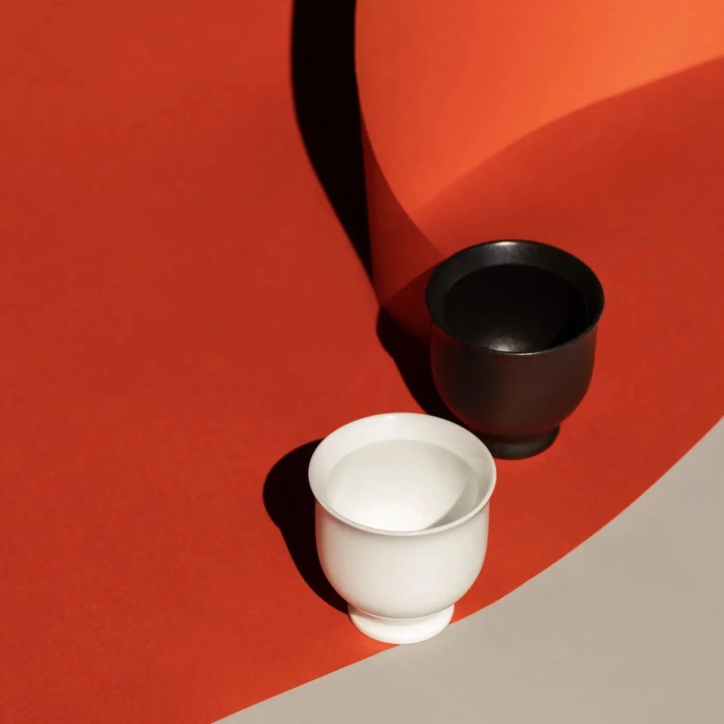 One black ORIGAMI Sensory Filter Cup is next to a white ORIGAMI Sensory Filter Cup with orange backdrop